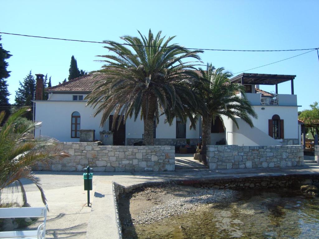 ein weißes Haus mit Palmen davor in der Unterkunft PRST 1 in Ugljan