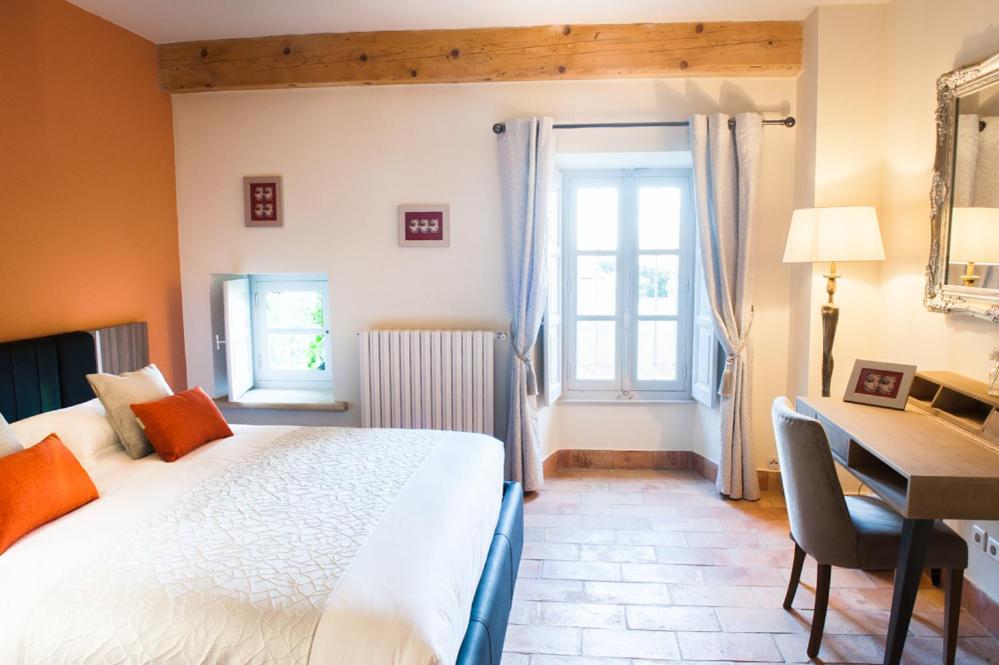 a bedroom with a bed and a desk and a window at Moulin de Vaucroze in Sorgues