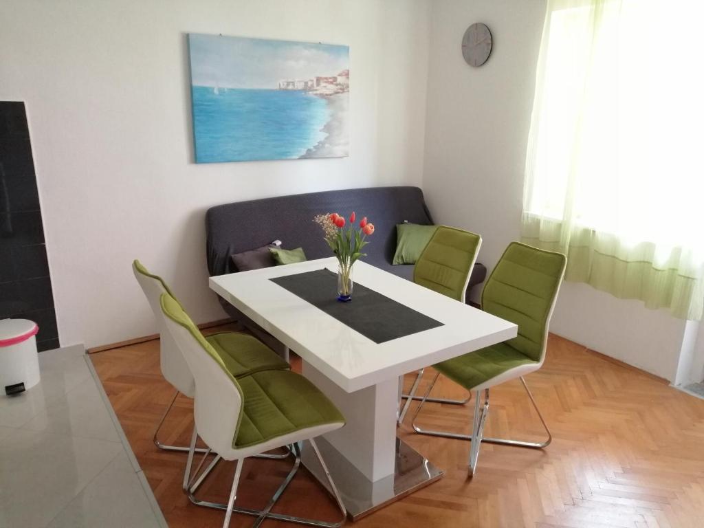 een eetkamer met een witte tafel en groene stoelen bij Apartment Antea in Šibenik