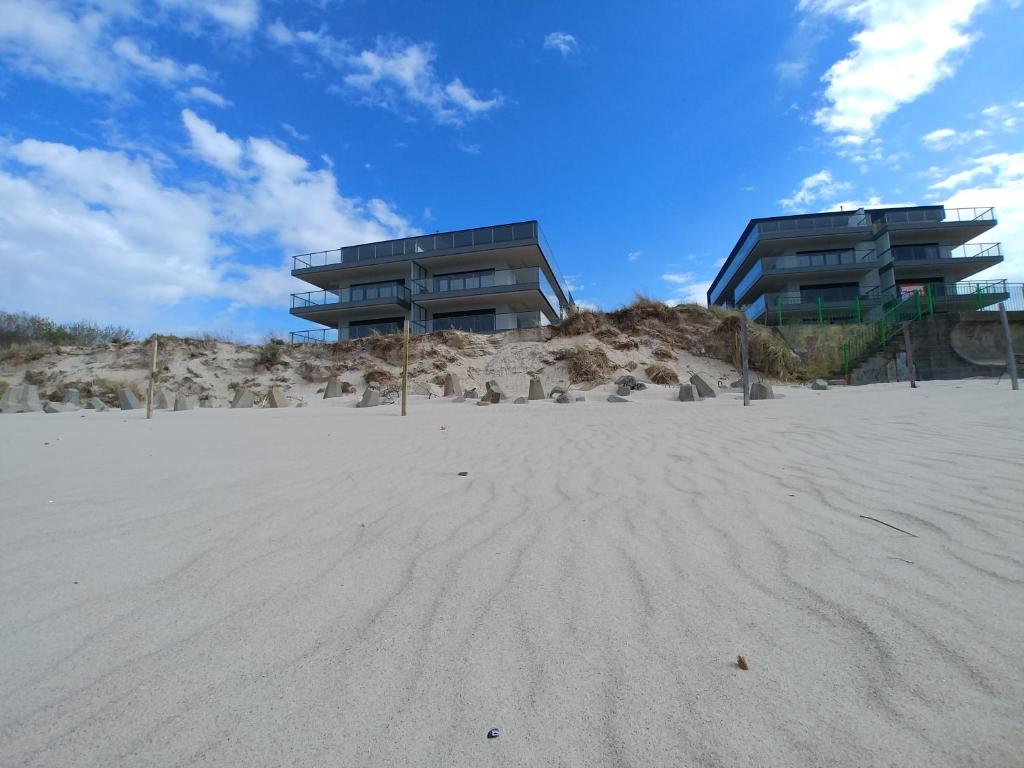 a building on top of a beach with a building at Apartament21 in Dziwnów