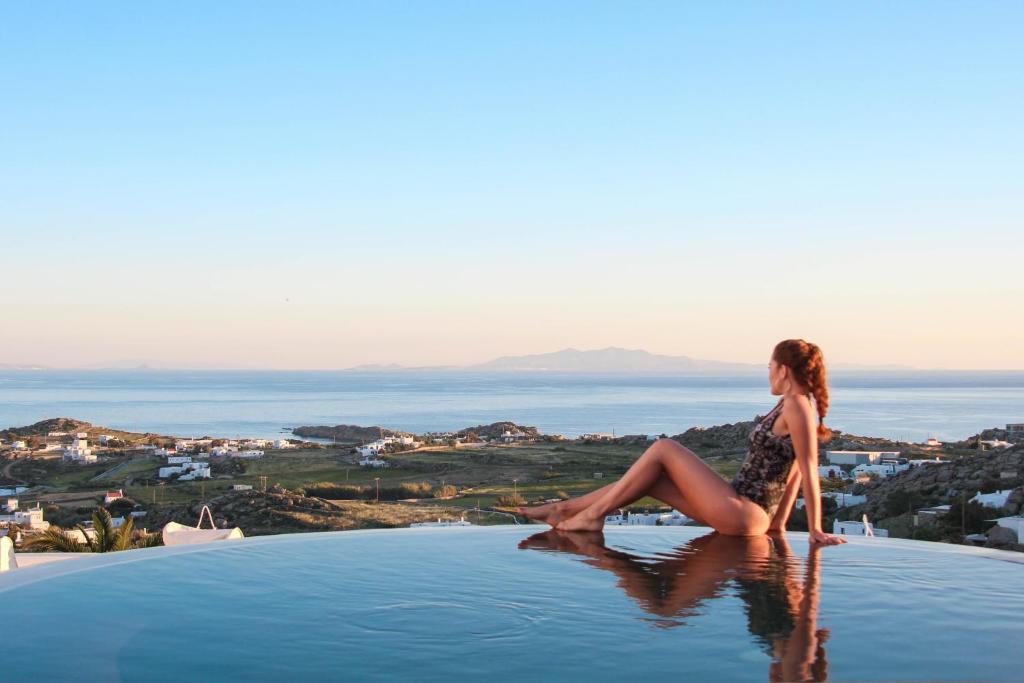 普拉迪斯亞羅斯的住宿－Sea & Stone Residence Mykonos，坐在游泳池边缘的女人