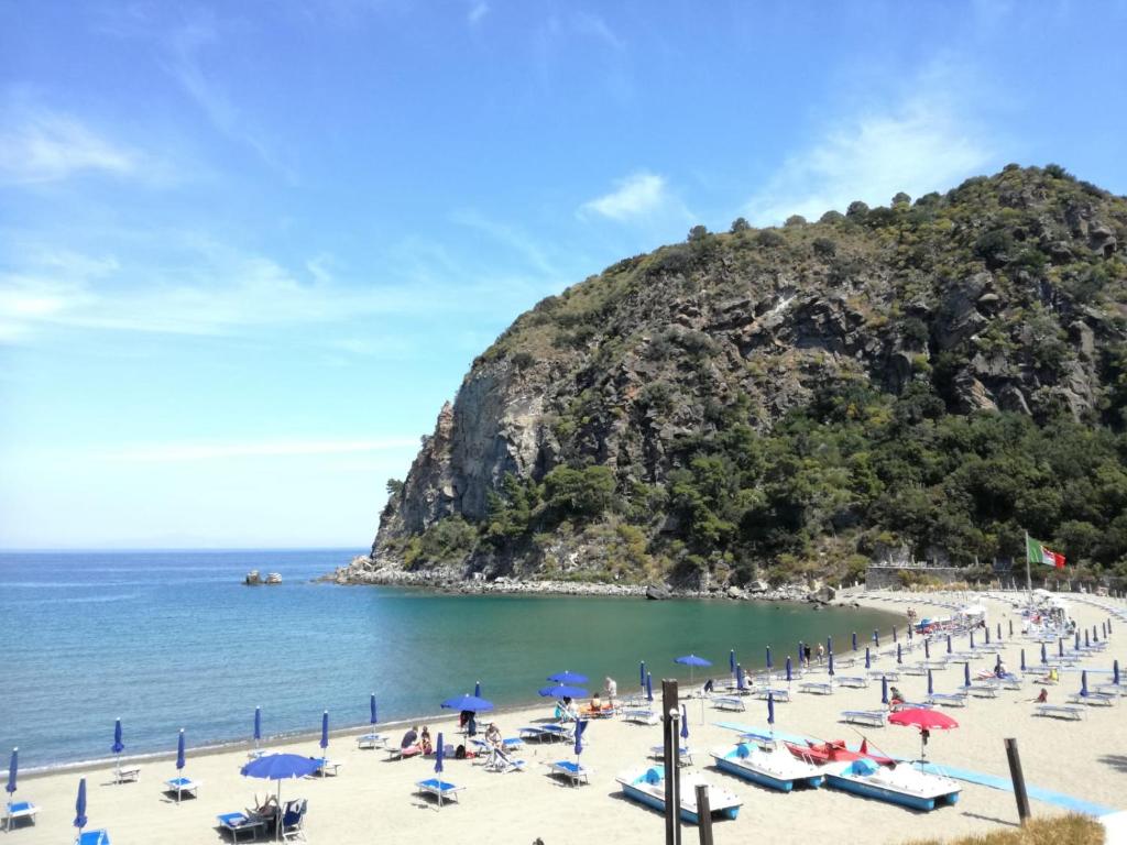 einen Strand mit Liegestühlen und Sonnenschirmen und dem Meer in der Unterkunft Villetta Baia San Montano in Ischia