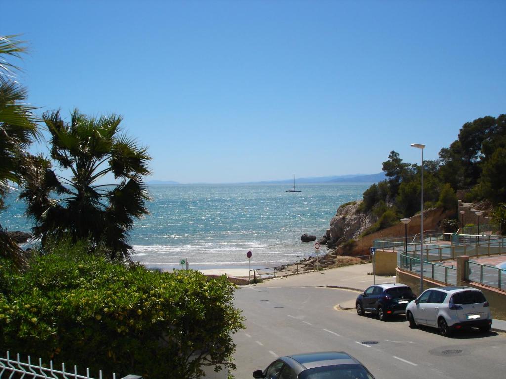 a beach with cars parked on a road next to the ocean at Legacy Apartments in Salou