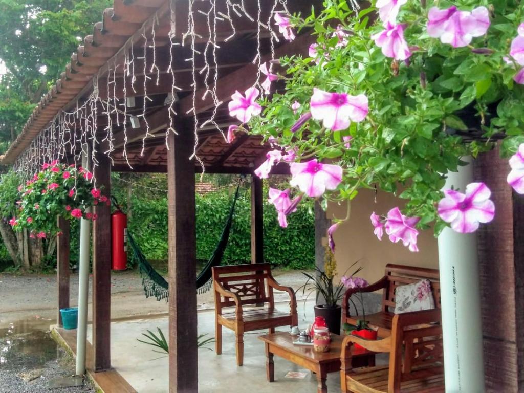 a pergola with a table and chairs and pink flowers at Pousada Casa do Bosque in Penedo