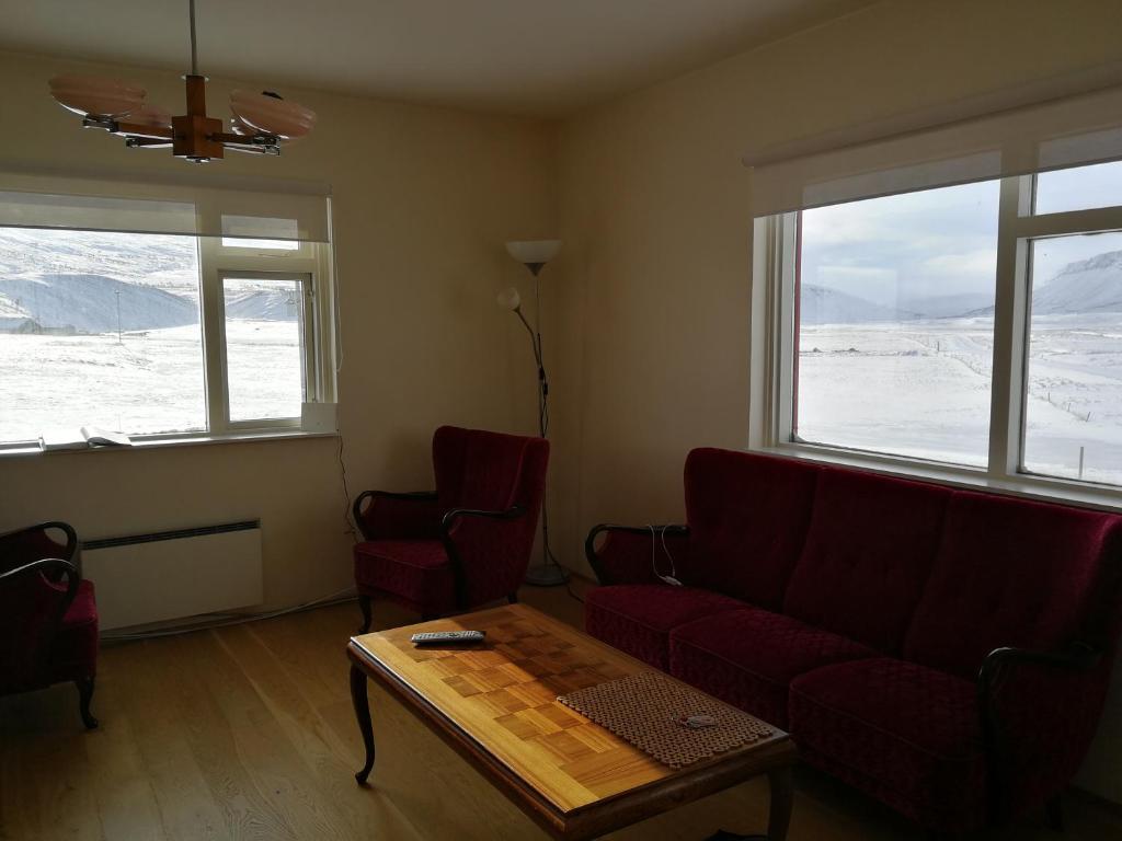 a living room with a couch and a table and two windows at Thorbrandsstadir Farm Holidays in Þorbrandsstaðir