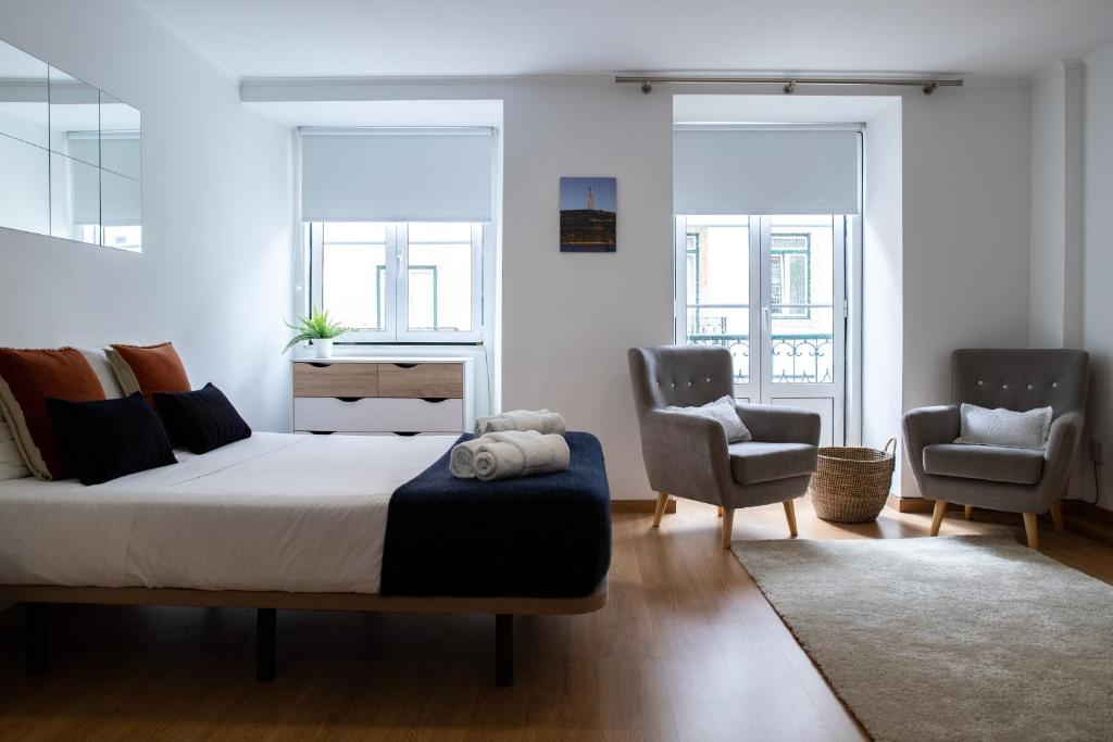 a bedroom with a large bed and two chairs at Belém - Fully equiped Studio in Lisbon
