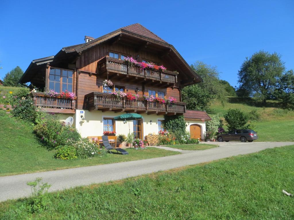 una casa con fiori sui balconi su una strada di Ferienwohnung Brigitte Perner a Nussdorf am Attersee