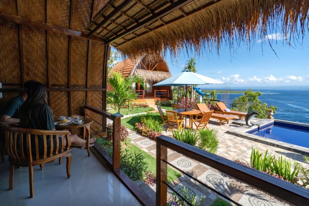 a woman sitting at a table on the balcony of a resort at Sundi Ocean Bungalow by ABM in Nusa Penida