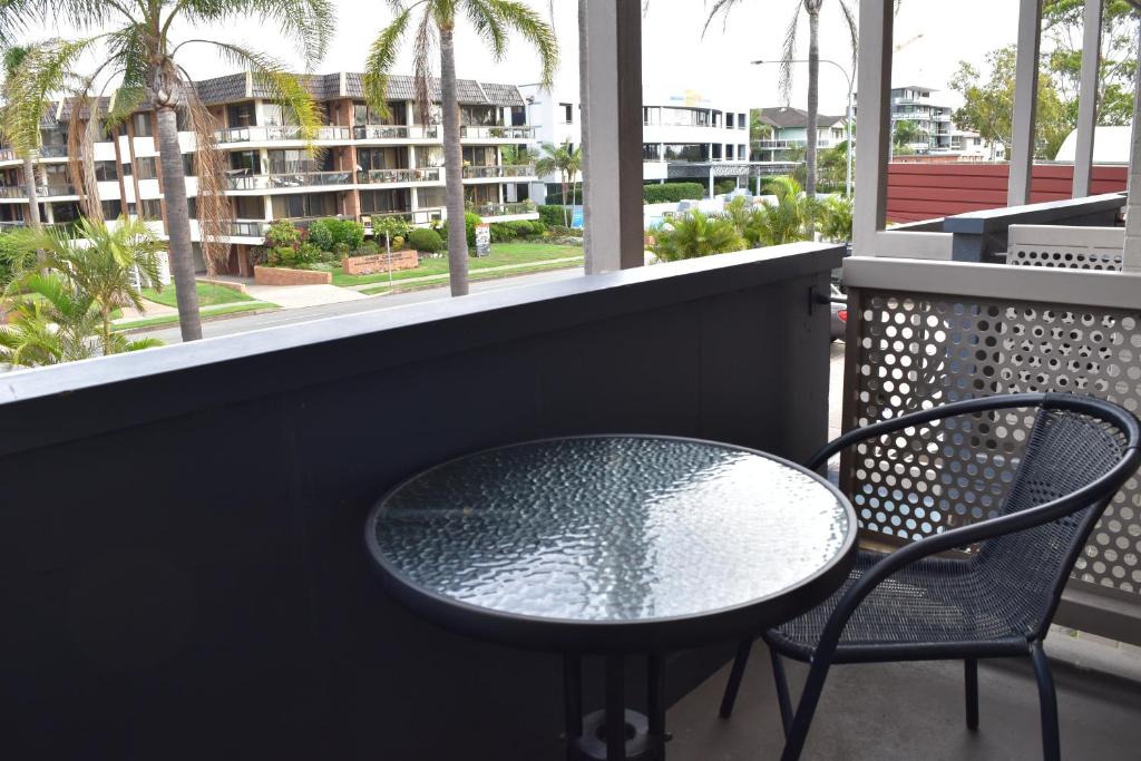a table and chair on a balcony with a view of a building at Comfort Resort Waters Edge in Port Macquarie