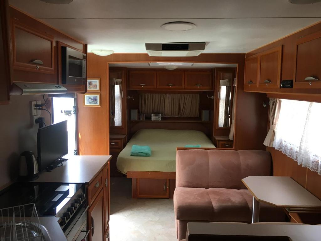 Comfortable caravan في كوكتاون: غرفة صغيرة بها سرير وأريكة ومطبخ
