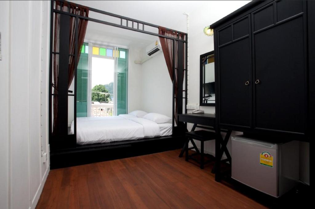 a bedroom with a bed and a desk and a mirror at 99 Oldtown Boutique Guesthouse SHA EXTRA PLUS in Phuket Town