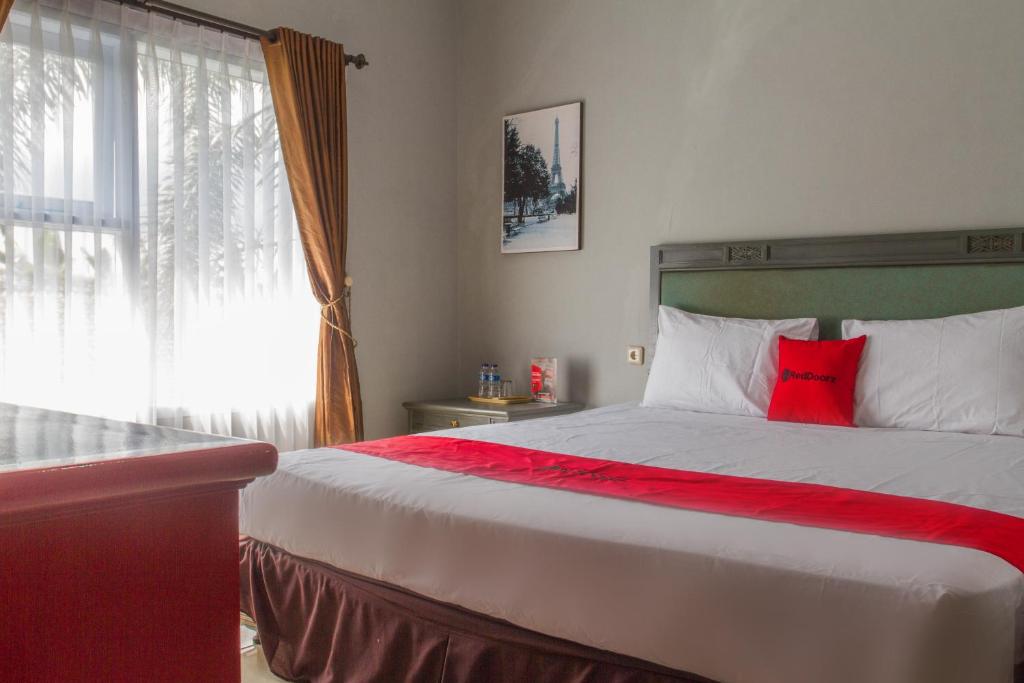 um quarto com uma cama grande e uma almofada vermelha em RedDoorz Plus @ Otista Garut em Garut