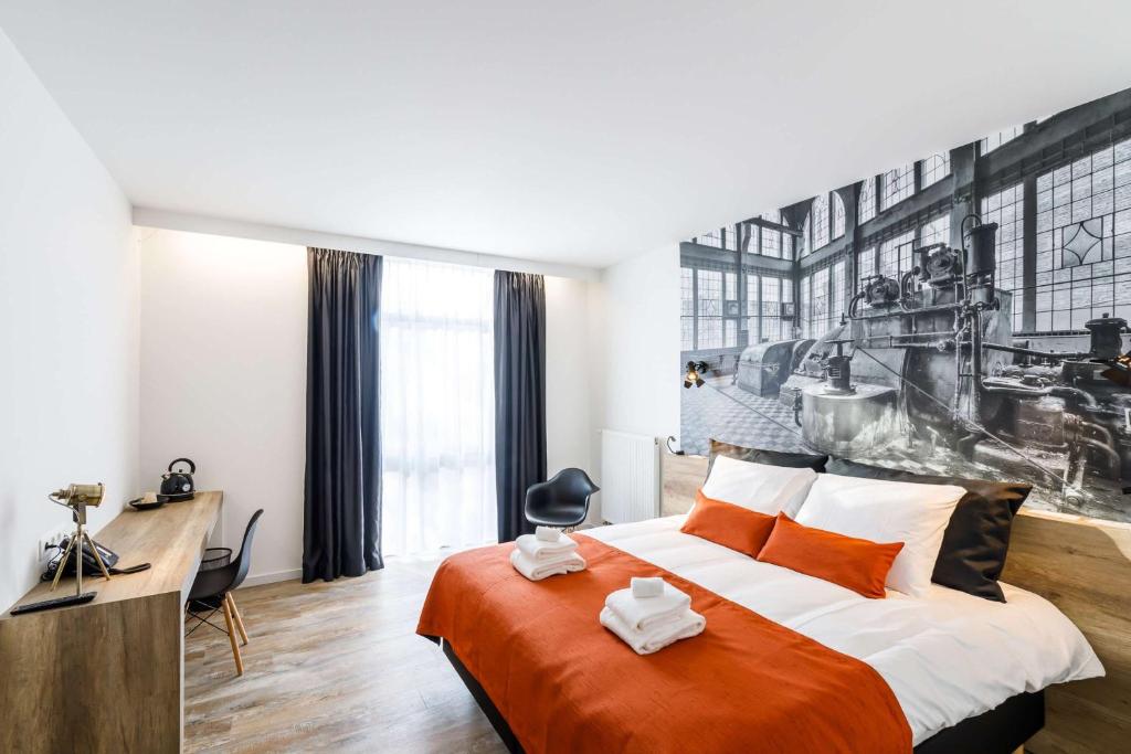 a bedroom with a large bed with an orange blanket at B-INN Lier in Lier