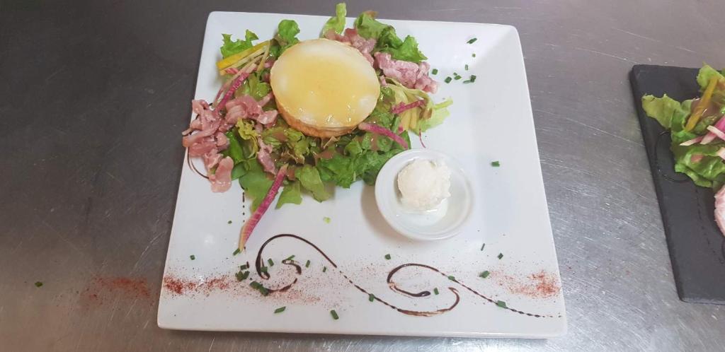 a white plate with a sandwich and salad on it at Logis Hôtels - Hôtel et Restaurant Les Cordeliers in Casteljaloux