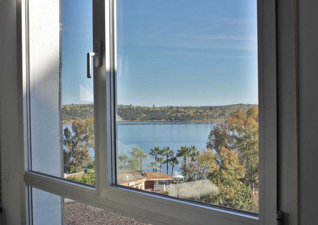 ein offenes Fenster mit Seeblick in der Unterkunft Apartamentos Embalse de Orellana in Orellana la Vieja