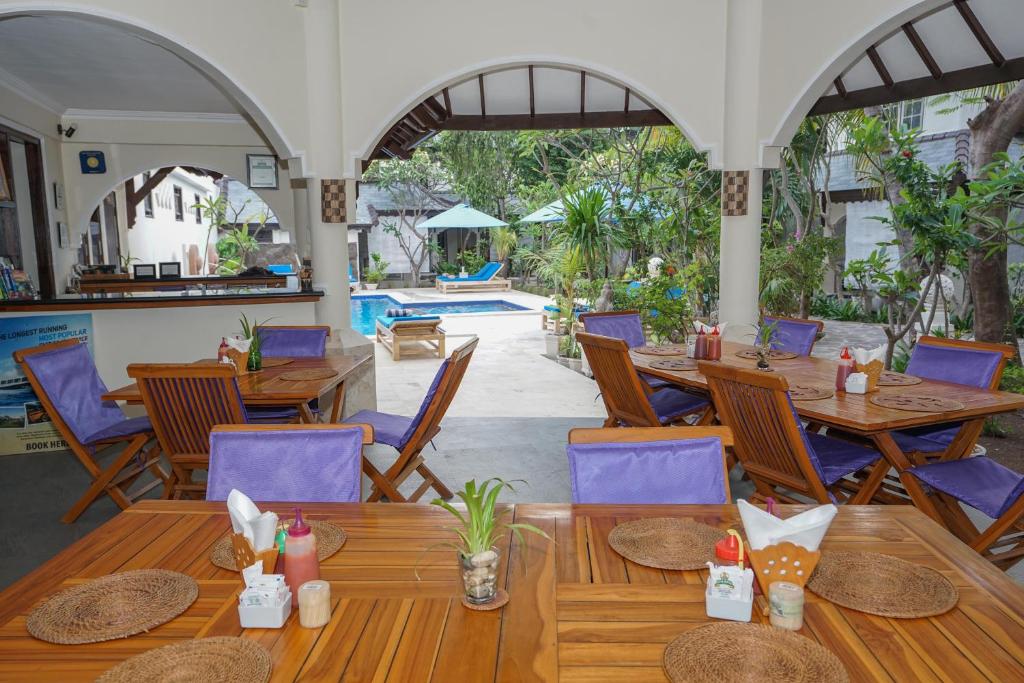 a restaurant with wooden tables and chairs and a pool at Martas Hotel in Gili Trawangan