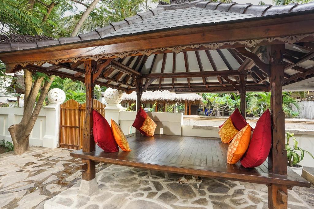 a wooden bench with colorful pillows sitting under a gazebo at Martas Hotel in Gili Trawangan