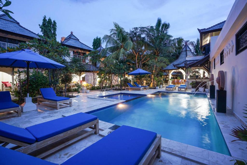 a pool at a resort with blue chairs and umbrellas at Martas Hotel in Gili Trawangan