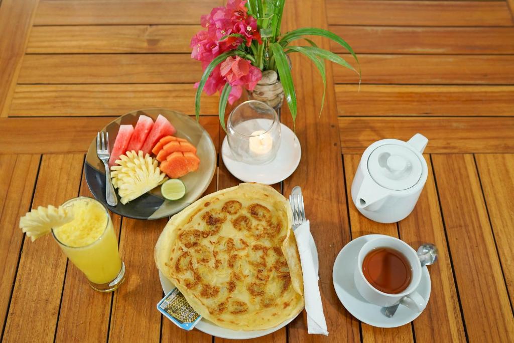 a table with a breakfast of quiche and fruit and a cup of coffee at Martas Hotel in Gili Trawangan