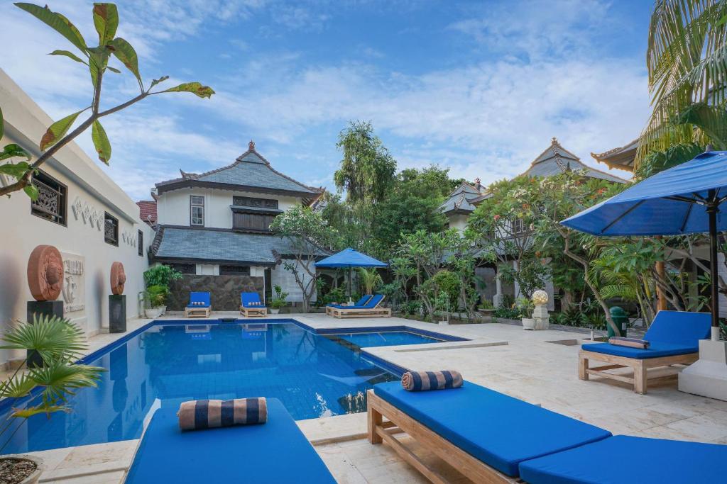 a swimming pool with blue chairs and a house at Martas Hotel in Gili Trawangan