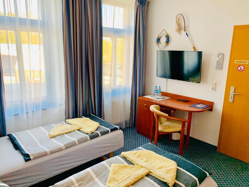 a hotel room with two beds and a desk with a television at Hotel-Pension "Petridamm" in Rostock