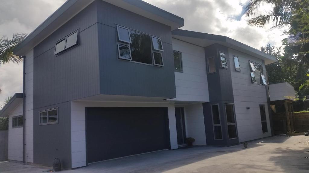 una casa en blanco y negro con garaje en Edgehill - semi self-contained eco friendly home, en Tauranga