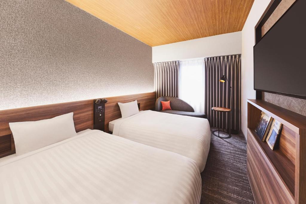 a hotel room with two beds and a tv at RIHGA PLACE HIGOBASHI in Osaka