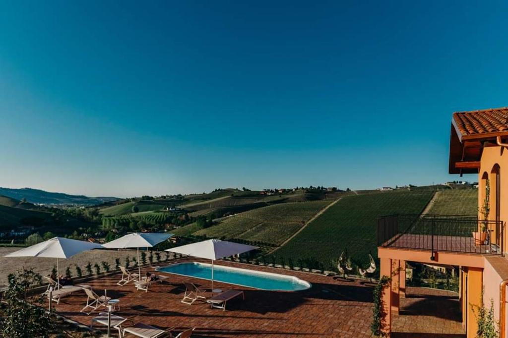 a building with a swimming pool next to a vineyard at Villa Garassino in Treiso