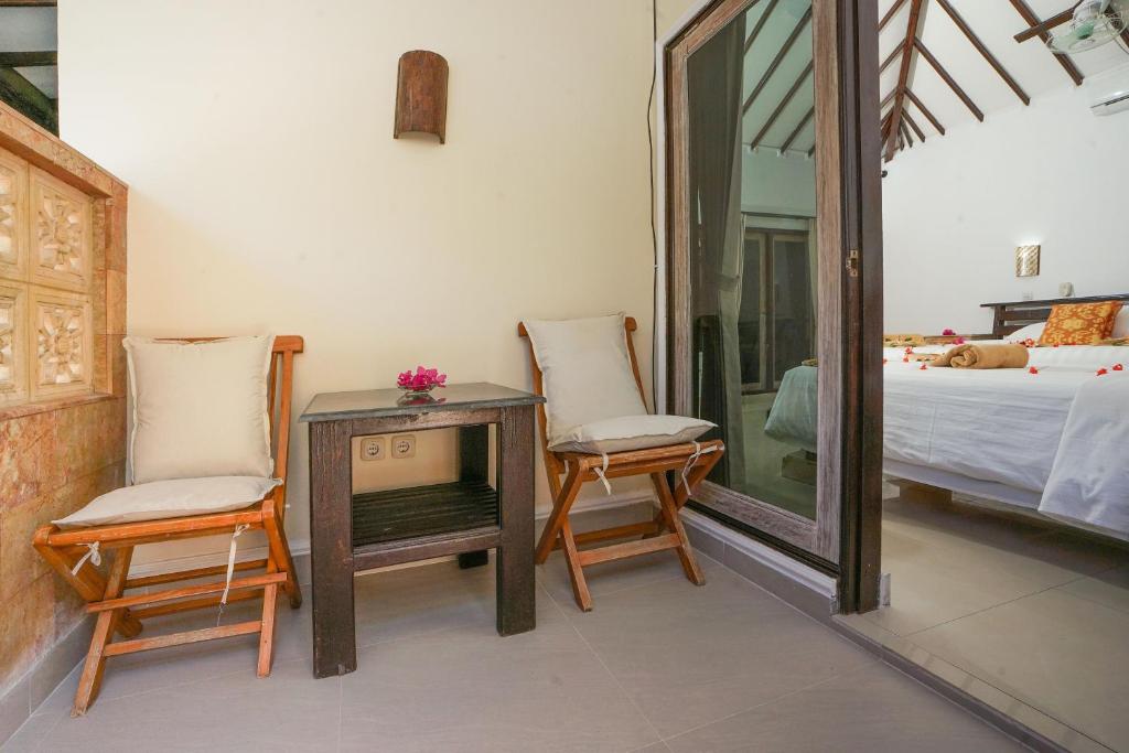 a room with two chairs and a table and a bed at Martas Hotel in Gili Trawangan