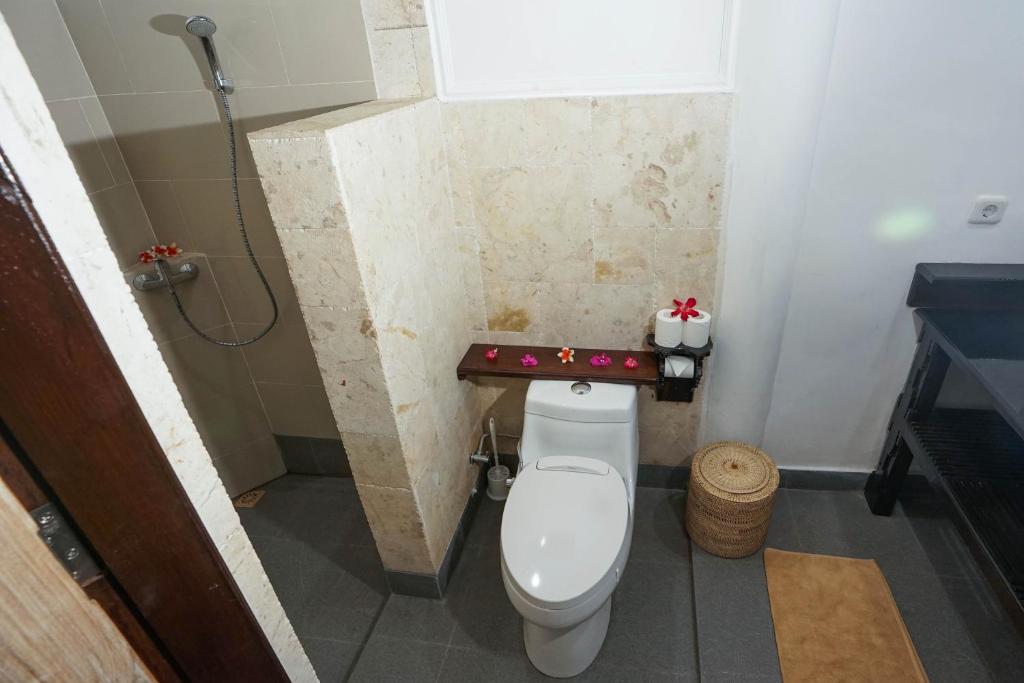 a bathroom with a toilet with a christmas shelf above it at Martas Hotel in Gili Trawangan
