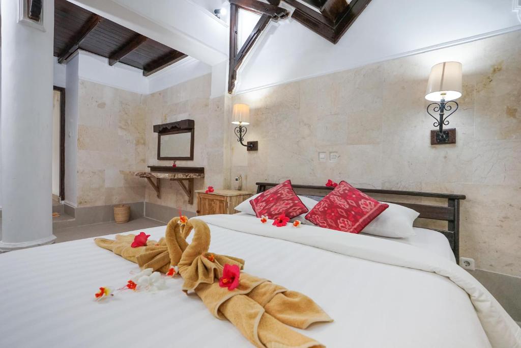 a bedroom with two white beds with red pillows at Martas Hotel in Gili Trawangan