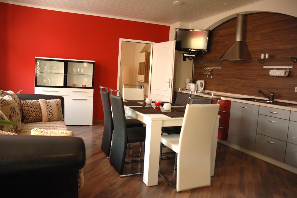 cocina con paredes rojas, mesa blanca y sillas en Apartments Stirl, en Dresden