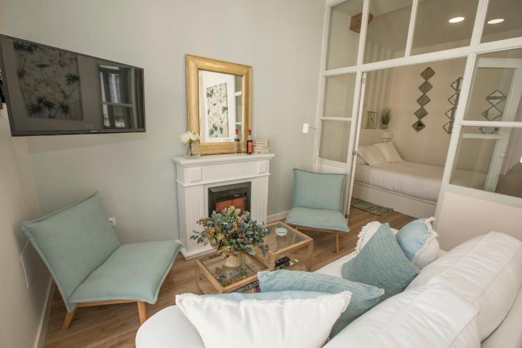 a living room with a couch and chairs and a fireplace at Gr Suites Boutique Catedral in Málaga