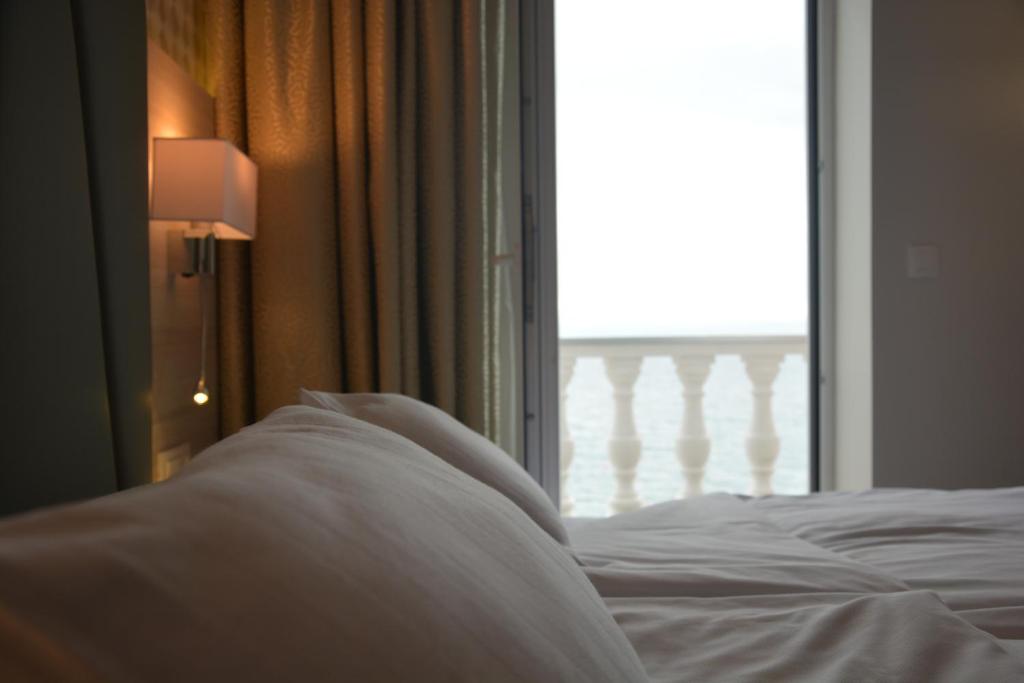 a bed with white sheets in front of a window at Hotel Fiesa in Piran
