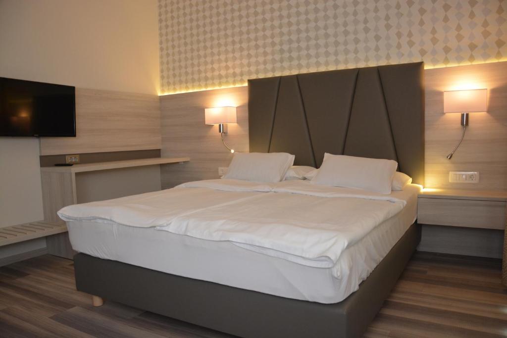 a bedroom with a large white bed with two pillows at Hotel Fiesa in Piran