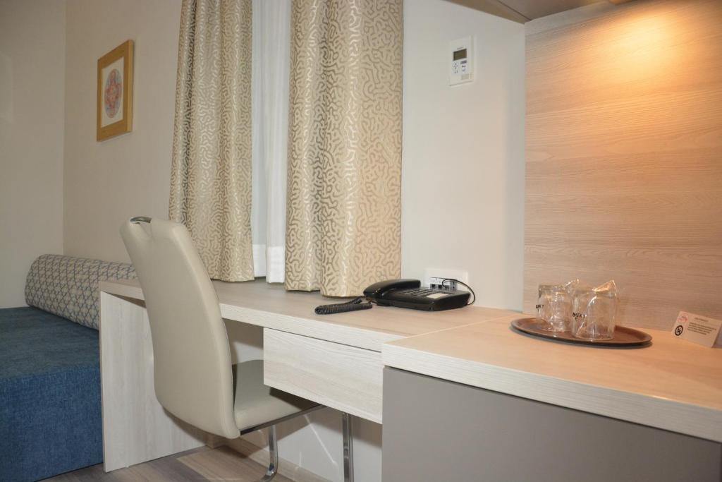 a room with a desk with a phone and a chair at Hotel Fiesa in Piran