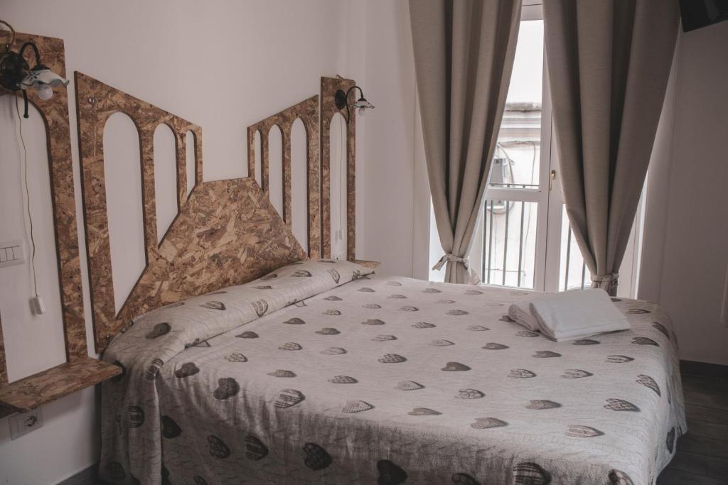 - une chambre avec un lit doté d'une tête de lit en bois et d'une fenêtre dans l'établissement Grande borgo, à Cava deʼ Tirreni