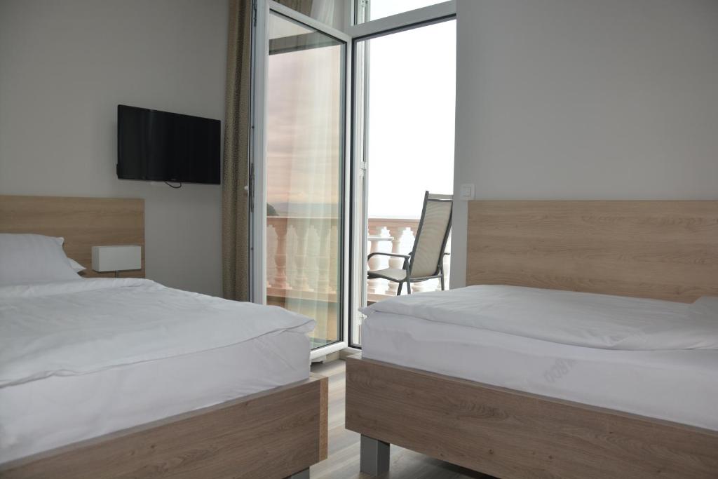 a bedroom with two beds and a balcony with a tv at Hotel Fiesa in Piran
