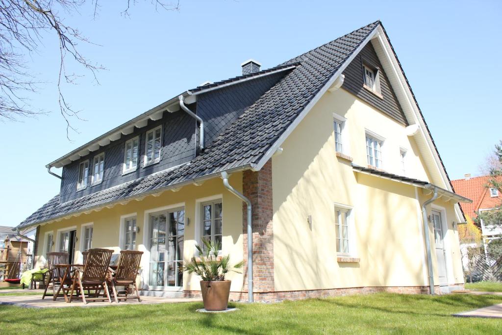 ein Haus mit schwarzem Dach und Stühlen in der Unterkunft Casa Ronja in Baabe