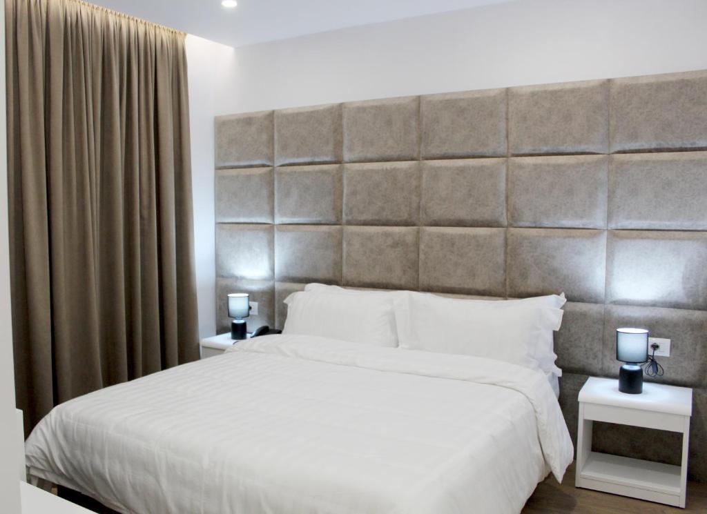 a bedroom with a large bed with a large headboard at Ramel Hotel in Tirana