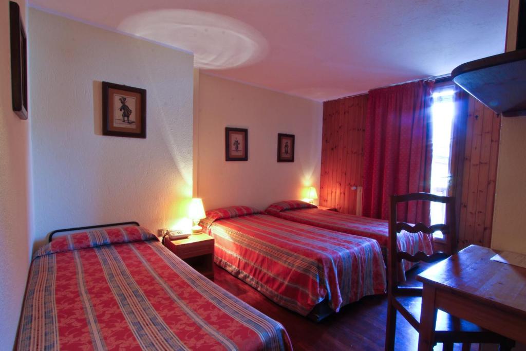 a hotel room with two beds and a table at Hotel Dolonne in Courmayeur