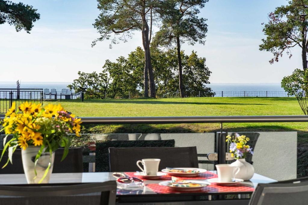 una mesa con un jarrón de flores en el balcón en Appartement Seemöwe - Oase am Haff en Garz-Usedom