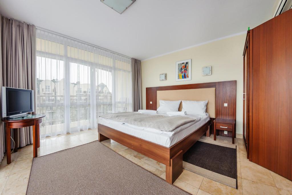 a bedroom with a large bed and a television at Avenue, Sun & Snow in Świnoujście