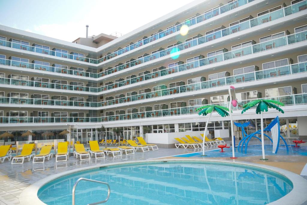 a large hotel with a swimming pool and chairs at Ohtels Villa Dorada in Salou