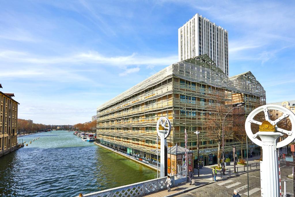 a large building next to a river next to a building at St Christopher's Inn Paris - Canal in Paris