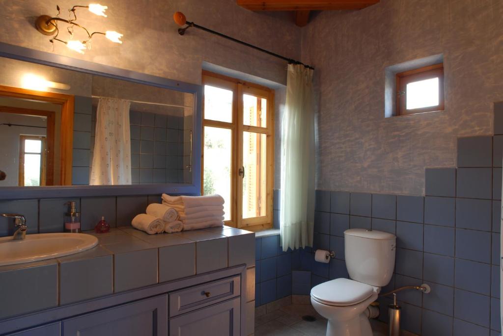 Un baño con inodoro, lavabo y espejo. en Mouses Apartments-Kardamyli, en Kardhamili