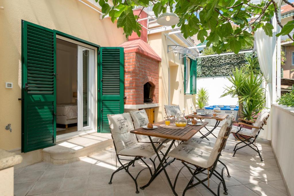 Un patio con mesa y sillas y una chimenea. en Villa Corona Split, en Split
