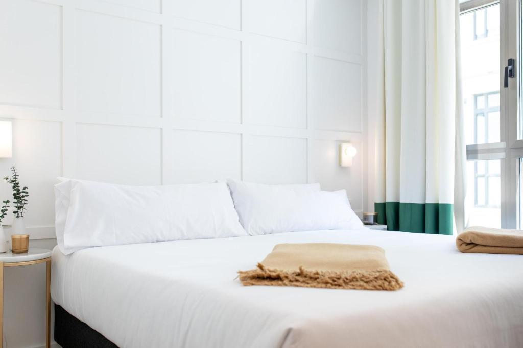 Cosmo Hotel Boutique في فالنسيا: سرير أبيض فوقه منشفة