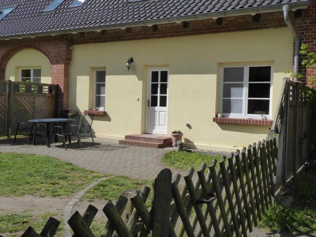 ein Haus mit einem Zaun und einem Tisch davor in der Unterkunft Ferienwohnung Ostseewald in Rostock