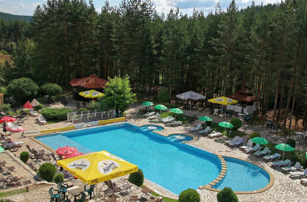 an outdoor swimming pool with umbrellas and chairs at Hotel Zora in Velingrad